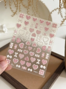 Close-up of 5D pink heart and bow embossed nail art stickers with candy designs