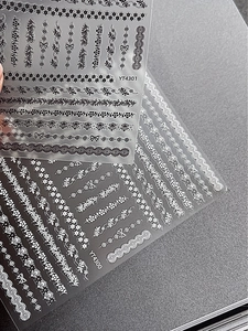 Macro detail of black and white 3D lace nail stickers with floral and bow patterns