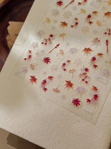 Macro detail of autumn leaf nail stickers with maple and ginkgo patterns and gold script