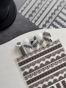 Detailed macro view of black and white lace nail stickers with vintage embossed patterns