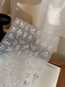 Gros plan d'autocollants 3D argentés gaufrés avec motifs papillons et fleurs pour ongles