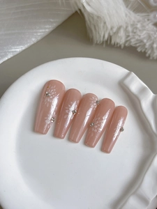 Detail of nude pink coffin press-on nails with white hand-painted flowers and tiny rhinestones