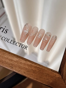 Détails macro d'ongles ballerine nude avec motifs floraux argentés 3D et perles