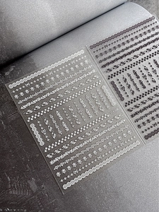 Detail showing black and white lace flower nail stickers with 3D embossed texture