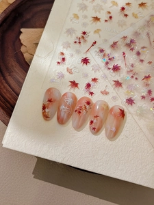 Detailed maple leaf nail stickers showing 3D embossed autumn designs on orange nails