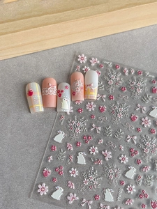 Detail of 3D embossed nail stickers featuring white rabbits, flowers, and bows for DIY