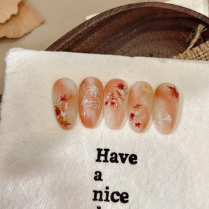 Autumn-themed maple leaf press-on nails with orange gradient and gold leaf patterns