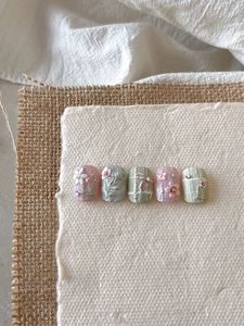 Detail of 3D embossed floral press-on nails with rhinestone and bow knot decorations