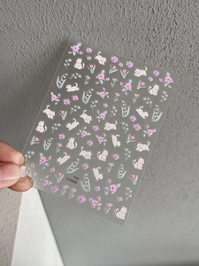 Close-up of cute cartoon white cat and floral nail stickers with transparent adhesive backing