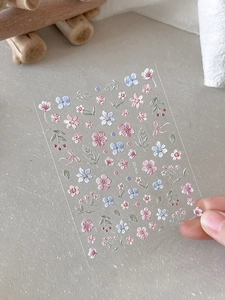 Detailed macro view of 3D embossed floral nail stickers with pink and blue garden patterns