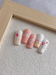 Macro shot of 3D bunny and floral embossed pink nail art set on a wooden frame background