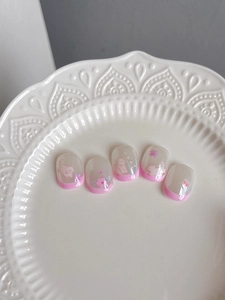 Detailed macro view of pink cartoon cat and floral nail art stickers on short oval nails