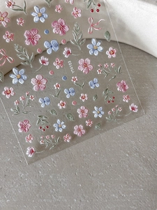Macro detail of 3D embossed floral nail stickers with pink flowers and green leaves