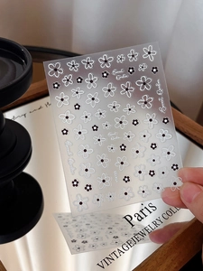 Macro detail of black and white 3D floral nail art stickers with daisy patterns