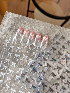 Macro shot of iridescent bowknot nail stickers and finished press-on nail art samples