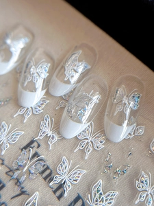 Detail of silver laser butterfly nail art on French manicure with Starlight text