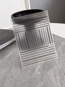 Detailed macro view of black lace and floral embossed 3D nail art stickers on clear base