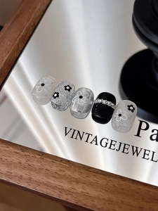 Detail of floral press-on nails with black white flowers and silver glitter texture
