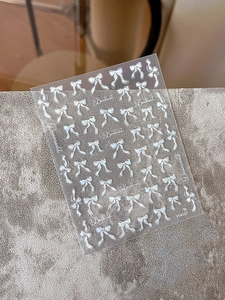 Macro shot of silver holographic bowknot nail art stickers showing laser shell effects