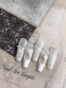 Detalle de pegatinas de uñas de encaje blanco de lujo con lazos 3D y perlas