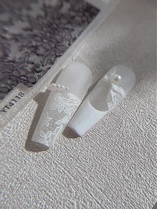 Foto macro de uñas postizas de trapecio largo con encaje, lazos en 3D y perlas finas