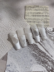 Detalle de pegatinas de uñas de encaje blanco con perlas y lazos 3D sobre base mate