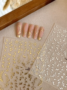 Detail shot of gold and silver leaf nail stickers with metallic embossed vine patterns