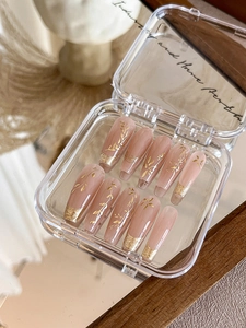 Macro detail of nude pink long square press-on nails with golden embossed leaf designs
