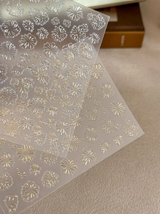 Detailed close-up of golden embossed firework nail art stickers with textured 3D finish