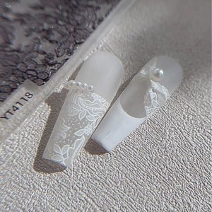 Uñas postizas con relieve de encaje blanco con perlas y lazo en forma de trapecio