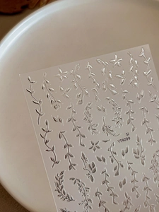 Macro shot of 3D chrome silver leaf nail decals with intricate star patterns