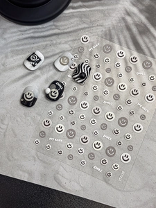 Detail view of 3D embossed smiley face nail stickers with black and white smile patterns