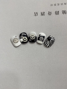 Detail of 3D embossed smiley face and zebra pattern press-on nails with black white decor