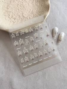 Détail de stickers nail art avec bouquets blancs et motifs de nœuds marron élégants