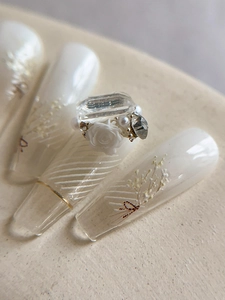 Détail macro d'ongles élégants avec fleurs 3D, perles et strass brillants