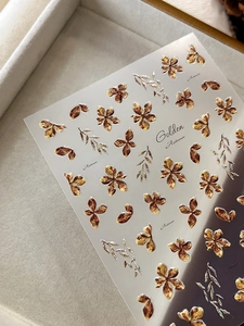 Detailed view of 3D gold flower nail stickers with autumn leaf patterns and metallic relief