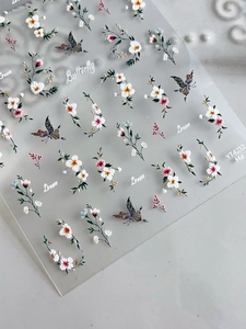 Détail de stickers à ongles fleurs et papillons avec touches dorées et lettrage chic