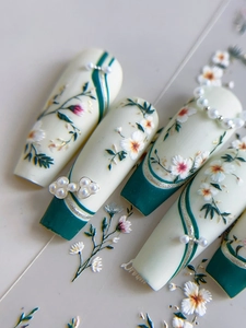 Détails de faux ongles floraux avec motifs papillon dorés et perles chic