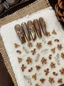 Detail of Golden Autumn nail stickers and gradient flower press-on nails on linen