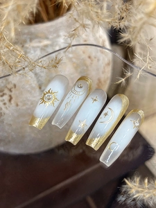Detail of long coffin press-on nails with gold celestial moon stars and sun designs