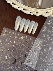 Detailed close-up of golden star and moon nail stickers applied on almond-shaped nails