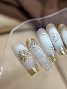 Macro detail of press-on nails with golden sun and moon patterns and rhinestones