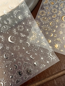 Detail of gold and silver starburst nail stickers with celestial sun and moon designs