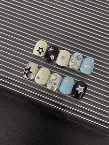Close-up of star pattern press-on nails with silver finish and blue rhinestones