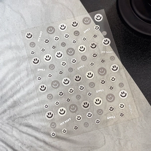 Minimalist nail art stickers with embossed smiles and text patterns on transparent backing