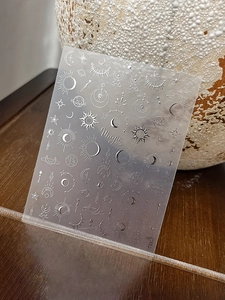 Detail of silver nail stickers with metallic stars and moon celestial patterns