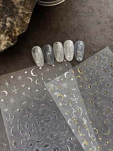 Detail showing gold and silver star moon nail stickers on dark stone texture background