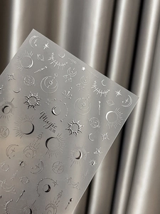 Detail of silver celestial nail art stickers featuring embossed moon and star designs