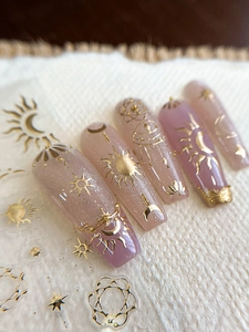 Detail of press-on nails with gold foil celestial sun moon star and geometric line patterns