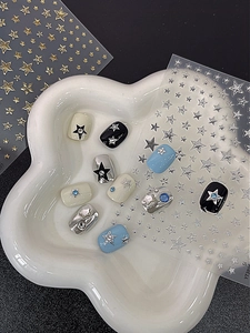 Detail shot of gold and silver star nail stickers with rhinestones on sample nails